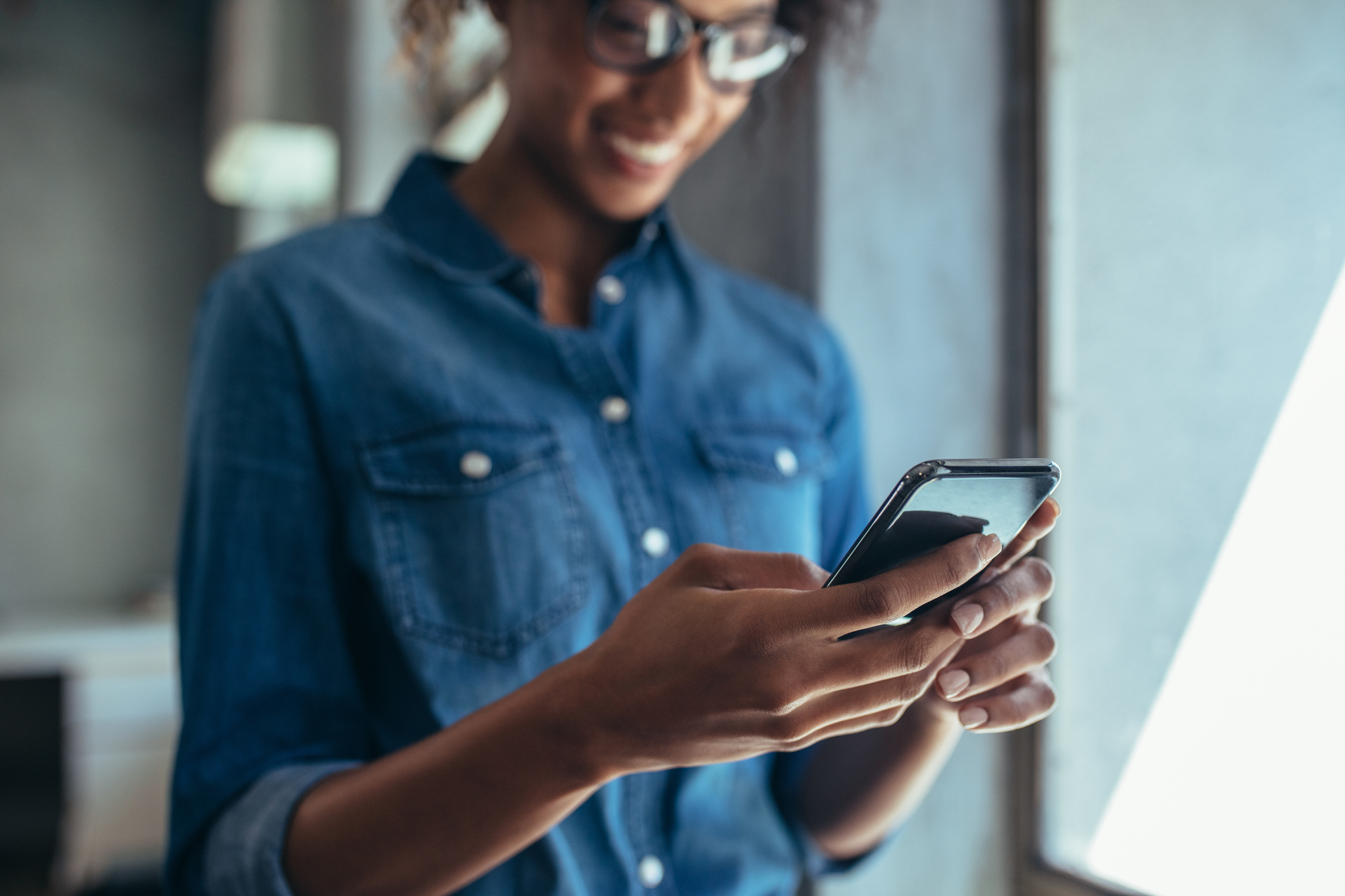Woman standing in office and using her smart phone.