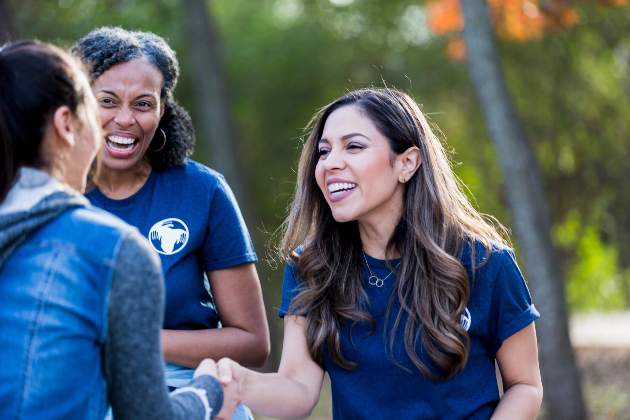 Two women greet and shake hands at volunteer event.
