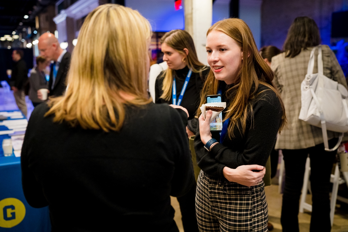 Women chatting in a crowded room at a networking event.