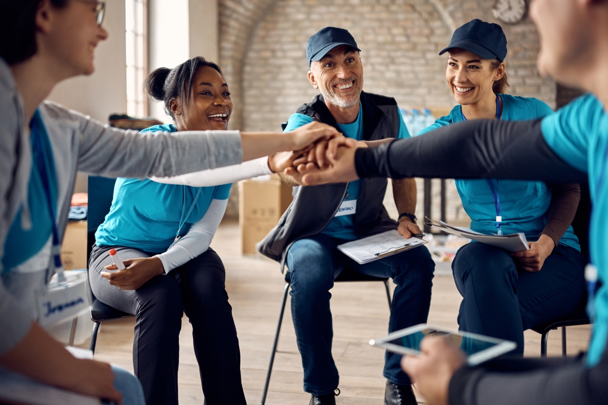 Team of motivated volunteers gather hands in unity after successful meeting.