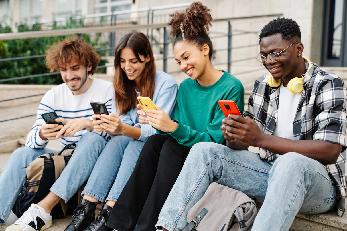 young alumni sitting on steps on their phones