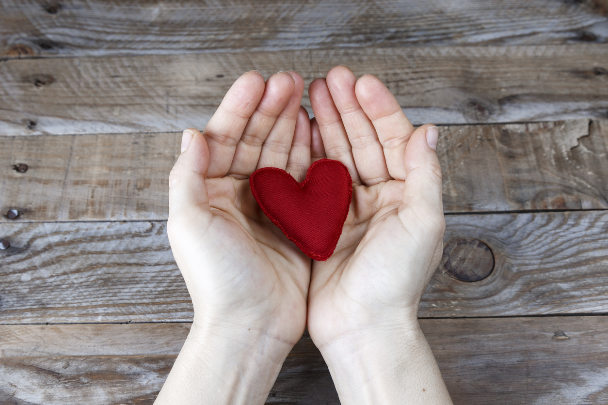 Red heart handmade on the hands of a woman